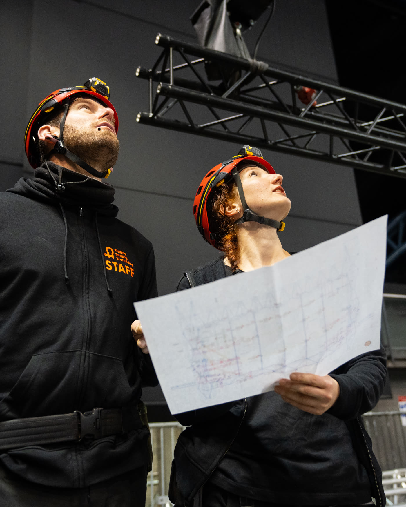Deux techniciens Rig'Up casqués consultant les plans de montage sur site